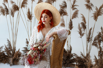 Wedding content - close-up Portrait of a young beautiful redhair girl in a studio sitting on a white background with a decorations. Copy space