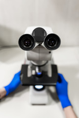 Closeup point of view of laboratory assistant looking through microscope lens