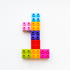 Number One made of colorful constructor blocks. Toy bricks lying in order, making number 1. Education process - learning numbers with child using multicolored toy details.