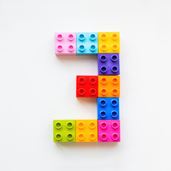 Number Three made of colorful constructor blocks. Toy bricks lying in order, making number 3. Education process - learning numbers with child using multicolored toy details.