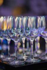 Glasses on the bar counter during a party. Transparent clean glasses in neon light on the bar prepared for drinks. 