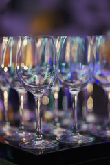 Glasses on the bar counter during a party. Transparent clean glasses in neon light on the bar prepared for drinks. 