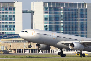 Close up of wide-body modern passenger airplane take off, building on background. Low over the runway.  Vacation, aviation, trip concept
