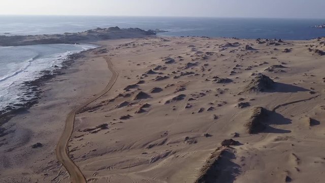 Las Tortolas beach aerial footage at Atacama Desert the sunset ray lights illuminate this amazing and idyllic beach in the middle of the desert, an arid awe landscape crashed by Pacific Ocean waters