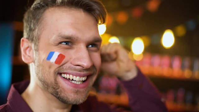 Joyful french fan with painted flag celebrating team victory, making yes gesture