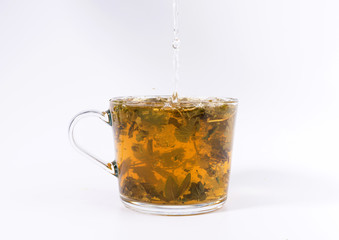 pouring hot water to the glass cup with tea, isolated on white background