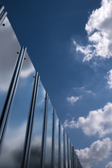 A stainless fence reflects the sky