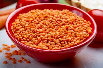 Dried orange lentils legume in red bowl