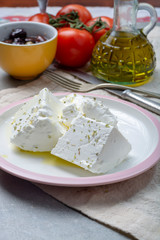 Fresh young soft white Feta cheese with olive oil on plate seasoned with dried oregano herb