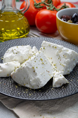 Fresh young soft white Feta cheese on black plate seasoned with dried oregano herb