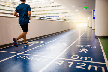 runner is running on blue running track in grand office building for employees to exercise and relax, Startup concept, Progress concept, Goal creation concept
