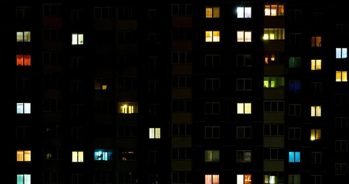 Night time lapse of Light in the windows of a multistory building. life in a big city