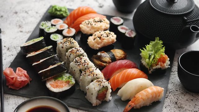 Assortment of different kinds of sushi rolls placed on black stone board