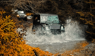 Mud and water splash in off-road racing. Off road sport truck between mountains landscape. Expedition offroader. Tracks on a muddy field. Road adventure. Adventure travel.