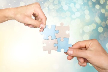 Human hands joining puzzle parts on background