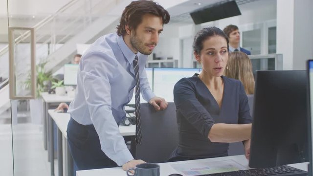 Two Professional Office Workers Work on Desktop Computer, Together Find Solution to a Problem and Cheerfully Celebrate Success by Doing High Five. Diverse Team of Beautiful People in Open Space Office