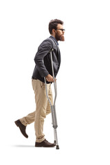 Young bearded man walking with crutches