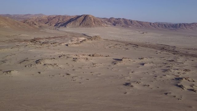Las Tortolas beach aerial footage at Atacama Desert the sunset ray lights illuminate this amazing and idyllic beach in the middle of the desert, an arid awe landscape crashed by Pacific Ocean waters
