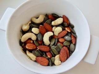 Cashew nuts, pumpkin seeds, salted and roasted almonds in a white bowl