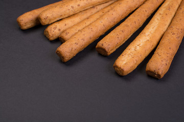 Crispy bread sticks on a black background.