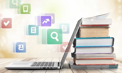 Stack of books with laptop on table