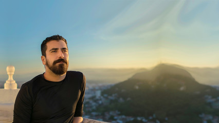 confident Isolated Hispanic latin arab indian bearded handsome man with optimistic look.  Blurred sunset city background. Plenty of horizontal copy-space in the sky. Positive dreamer banner concept