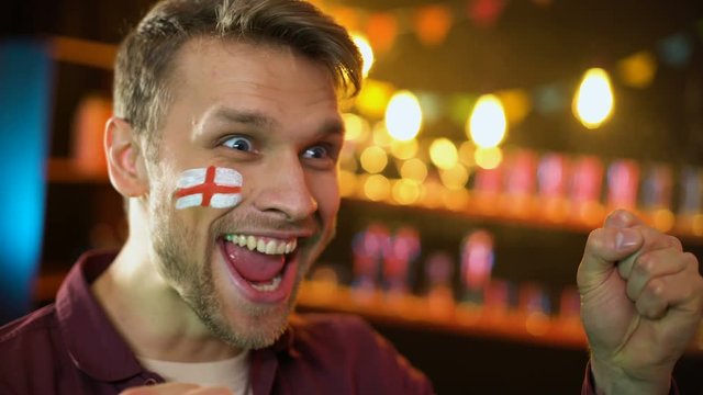 Satisfied english football team supporter with flag painted on cheek cheering