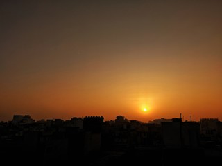 Sunrise over a cityscape silhouette.