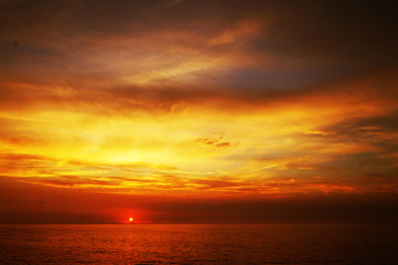 Fototapeta premium Rich golden and orange coastal sunset with detailed cloud and the open sea. United Kingdom