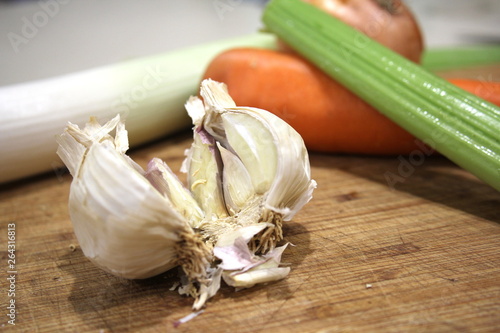 Garlic with carrot and celery on chopping board, vegetables on wooden cutting board