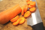 Macro Sliced carrots, vegetable preparation, slicing carrots on wooden board 