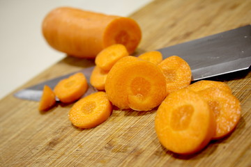 Macro Sliced carrots, vegetable preparation, slicing carrots on wooden board 