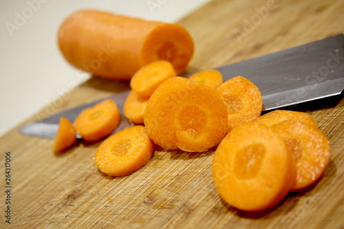 Macro Sliced carrots, vegetable preparation, slicing carrots on wooden board 