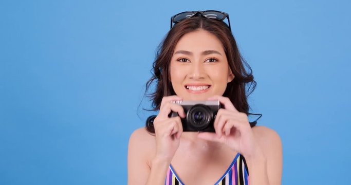 Portrait of beautiful asian woman using mirrorless camera with happy emotion at blue background. People with technology concept.
