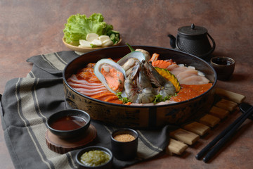 Side of beef garnished with sesame, and shellfish with prawns arranged on the tray combined with vegetables for grill set on the table.