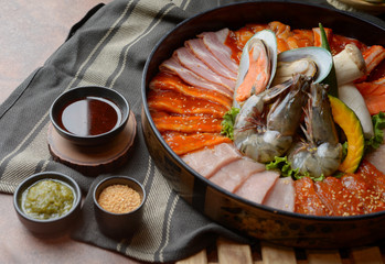 Side of beef garnished with sesame, and shellfish with prawns arranged on the tray combined with vegetables for grill set on the table.