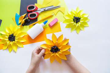 hands of the child makes an odd flower paper out of sunflower. Yellow plant summer. The creative...