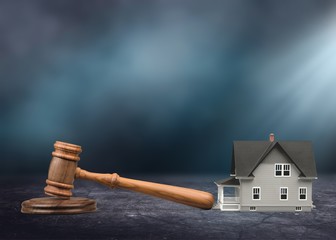 Judge hammer and house on brown wodden table and wall background