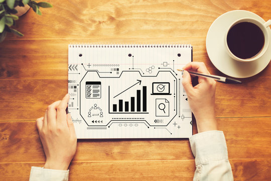 Marketing concept with a person writing in a notebook on a wooden table - Powered by Adobe