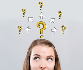 Big and small question marks with arrows with young woman looking upwards