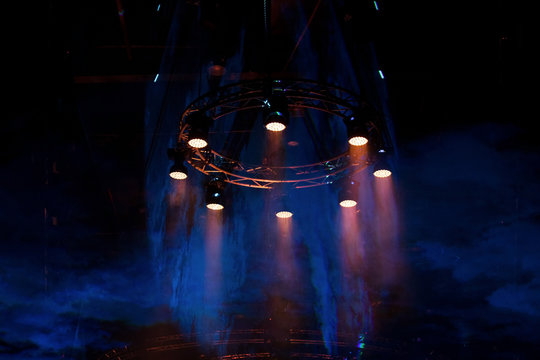 Performance moving LED Par lighting on construction light beam ray downward in yellow blue color with smoke, on Concert and Fashion Show stage ramp, low light exposure with grain and noise