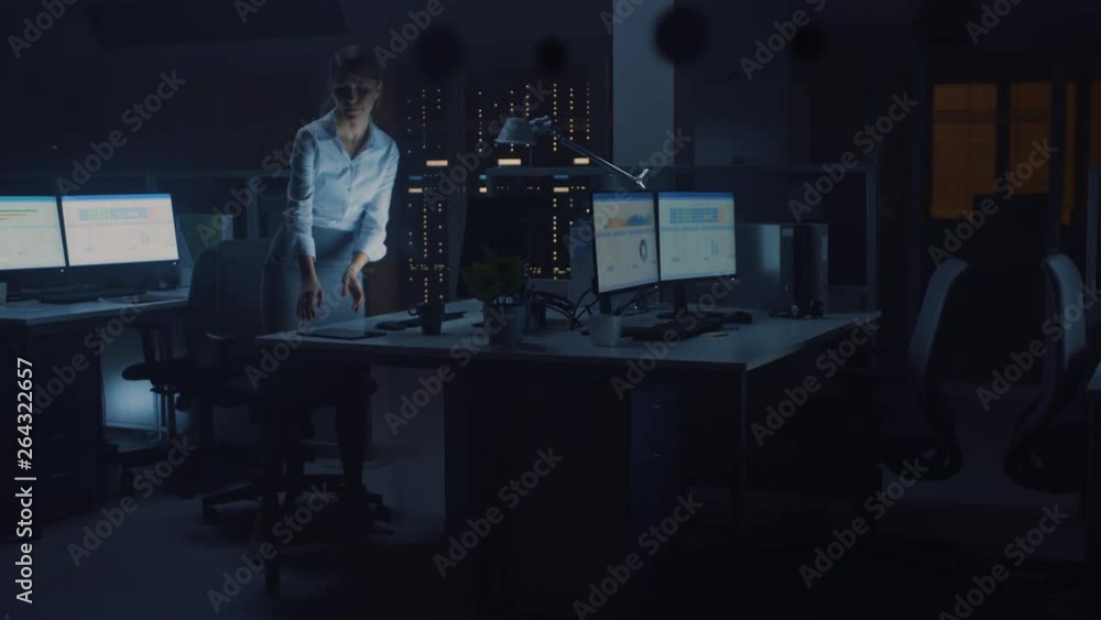 Poster working late at night in the office: businesswoman using desktop computer, analyzing, using document