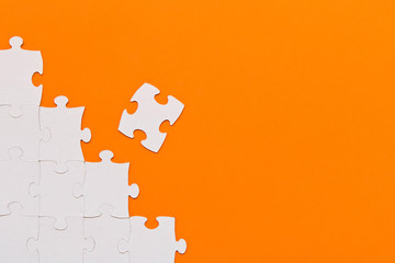 White jigsaw puzzles on orange background. The concept of development of thinking.