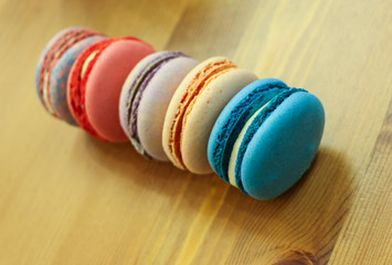 tasty macaroon cake of different colors on wooden background