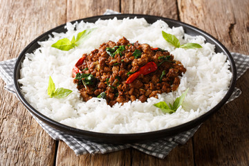 Traditional basil chicken with chili pepper and soy sauce with rice garnish close-up on a plate. horizontal