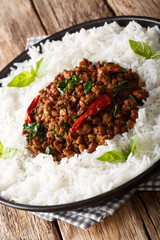 Thai Basil Chicken (Gai Pad Krapow) with rice close-up on a plate. vertical