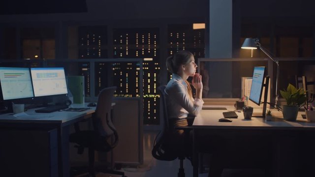 In the Office at Night, Overworked Tired Female Worker Uses Desktop Computer but Falls Asleep Fast. Tired Frustrated Exhausted Businessman Falls asleep at Her Job