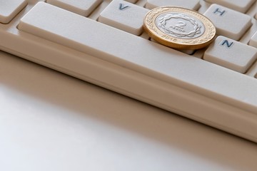 Coin in two pesos on the computer keyboard close-up. Online business in Argentina. International sales on the Internet. Copy space.