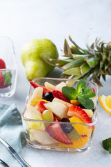 Bowl of fresh summer fruit salad on white stone background. Healthy food. Copy space
