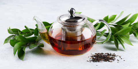 Glass teapot of black tea, loose leaf tea on a white background